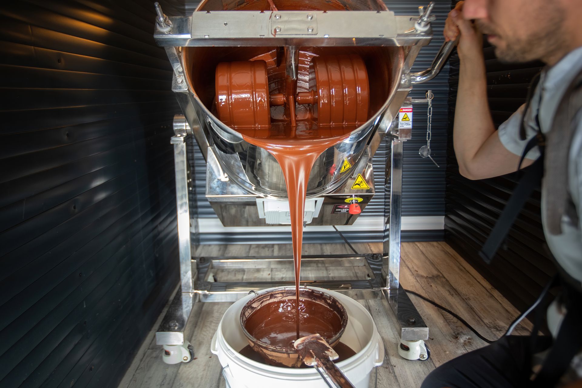 Le chocolat coule d'une mélangeuse en inox dans l'atelier de la Chocolaterie du Nouveau Monde.